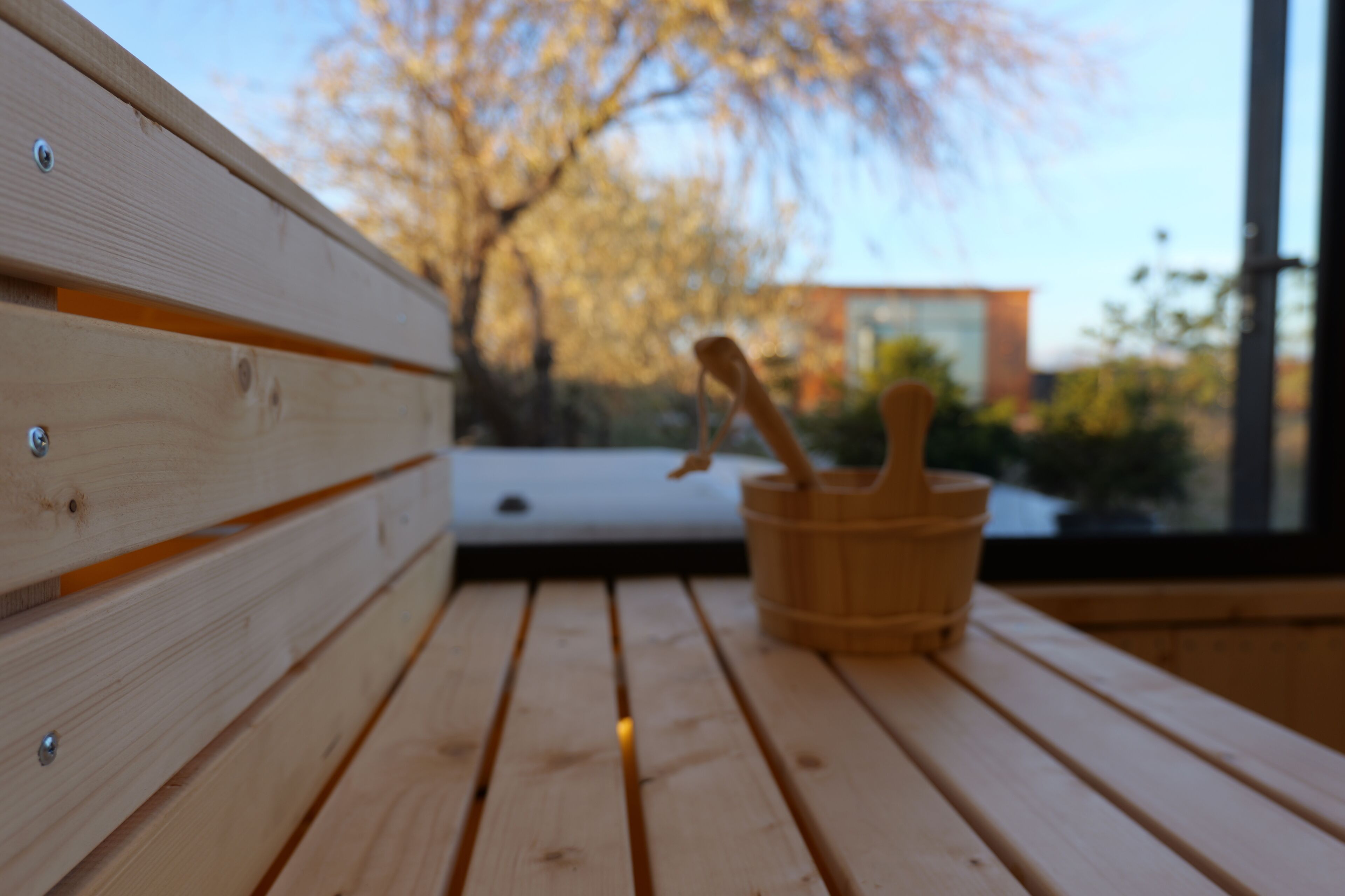A wooden bench with a wooden bucket and a spoon.