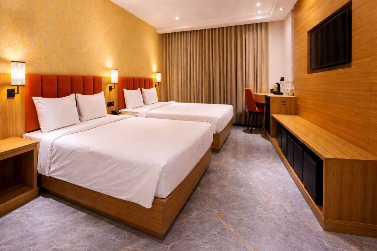 A hotel room with two beds, a desk, a TV, and a curtain.