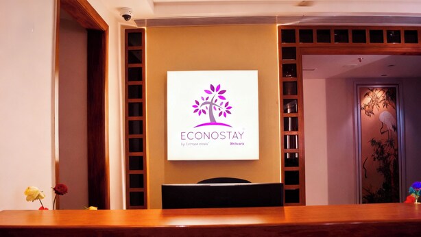 A reception desk with a logo, a wooden reception desk, and a wall-mounted sign. - Econostay (Bhilwara)