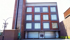 A modern building with a brick facade, multiple windows, and a garage door. - Econostay (Bhilwara)