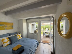 A bedroom with a bed, a fan, a sliding glass door leading to an outdoor patio with chairs and a table.