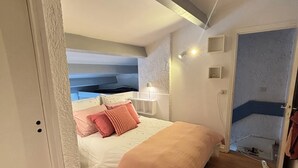 A bedroom with a bed, bedside table, lamp, and a door leading to another room. - Villa Olinka, behind the dune, plage des Bourdaines (Seignosse)