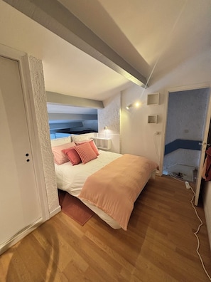 A bedroom with a bed, bedside table, lamp, and a door leading to another room. - Villa Olinka, behind the dune, plage des Bourdaines (Seignosse)