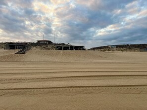 Una playa arenosa con un edificio y una escalera que lo conecta.