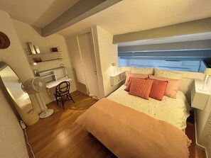 A bedroom with a bed, bedside tables, a desk, a chair, and a wardrobe.
