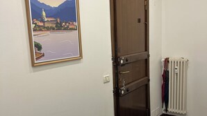 Una habitación con puerta de madera, un cuadro en la pared, un radiador y suelo de madera.