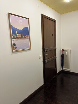 A room with a wooden door, a framed picture on the wall, a radiator, and a wooden floor. - Amazing studio appartment, newly renoveted, walking distance to Como. (Como)