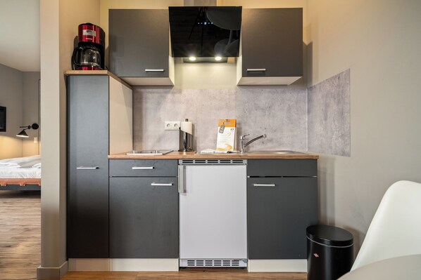 A compact kitchen with a dishwasher, a coffee maker, and a sink.