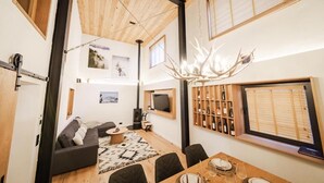 Una sala de estar moderna con un sofá, una mesa de comedor y un gran techo de madera.