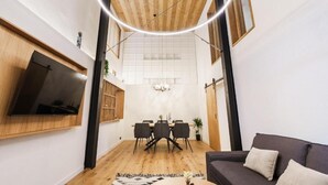 Una sala de estar moderna con un televisor de pantalla plana, un comedor con candelabro y un sofá.