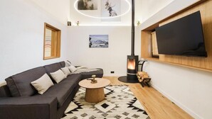 Una sala de estar moderna con un sofá, una mesa redonda de centro, una chimenea y un televisor montado.