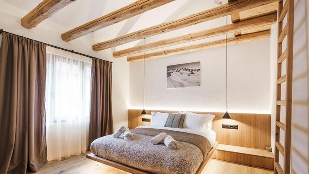 Un dormitorio con techo de madera, una cama con cabecera, una mesita de noche y un cuadro colgado en la pared.