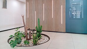 Una zona de recepción con un muro de listones de madera, una planta de cactus y un letrero que dice 'BLUE WAVE'.