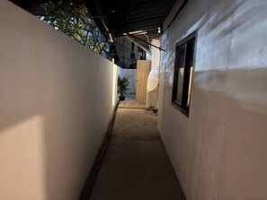 A narrow corridor with white walls, a potted plant, and a window on the right. - D6 Apartments at the Pier 2 of 6 (Ko Pha-ngan)