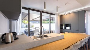 Una cucina moderna con una grande isola, un lavello incassato e un'area pranzo con sedie.