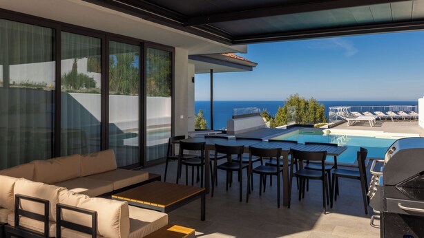 Patio moderno all'aperto con piscina, area relax e vista sull'oceano.