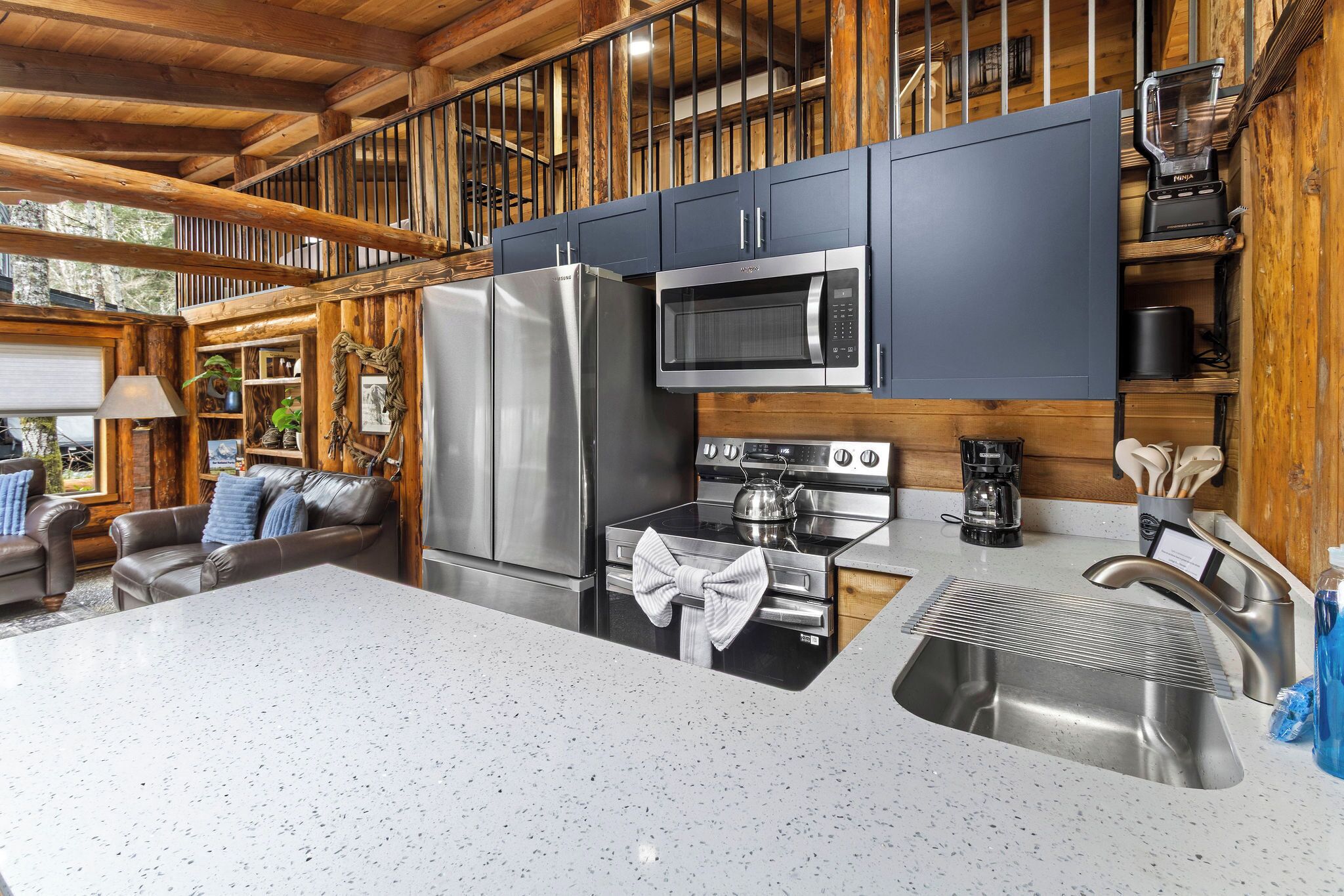 A modern kitchen with stainless steel appliances, a large island with a sink, and a cozy seating area with a fireplace.