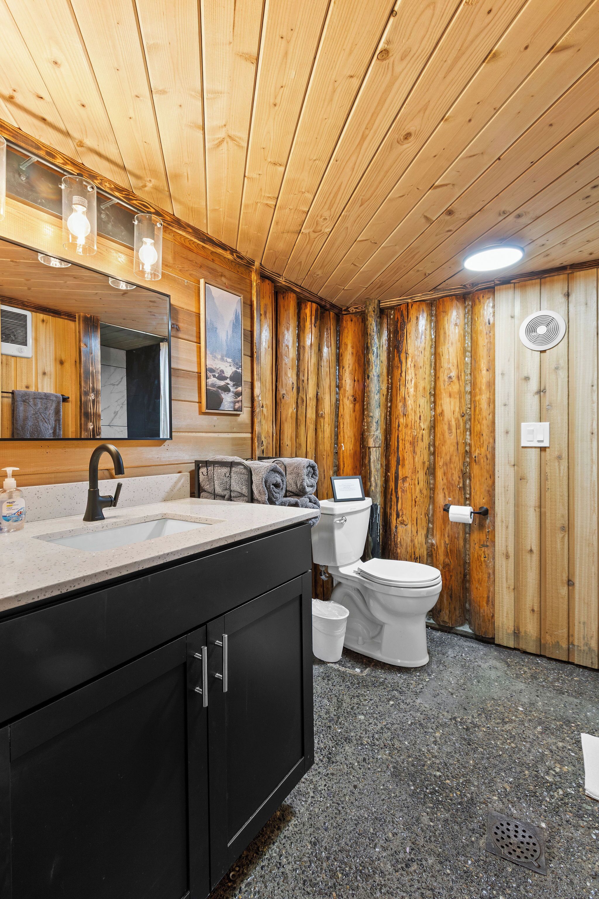 A wooden interior with a sink, toilet, and mirror.
