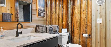 A wooden interior with a sink, toilet, and mirror.