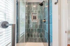 A shower with blue tiles, a glass door, and a control panel. - Mountain Valley Hideaway: a serene 2-acre retreat in southwest Virginia, near top hiking trails, with stunning views and a cozy outdoor fire pit. (Catawba)