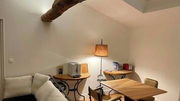 Une pièce de taille modeste, comprenant un canapé, une table à manger, une lampe et un plafond avec une poutre en bois.