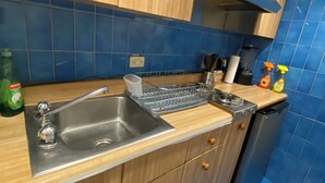 Una cucina con lavello in acciaio inossidabile, mobili in legno, scolapiatti e pareti rivestite di piastrelle blu.