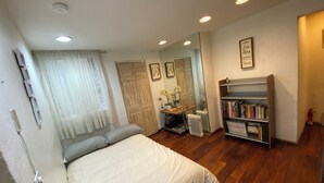 Una camera da letto con un letto, una libreria, un termosifone e uno specchio.