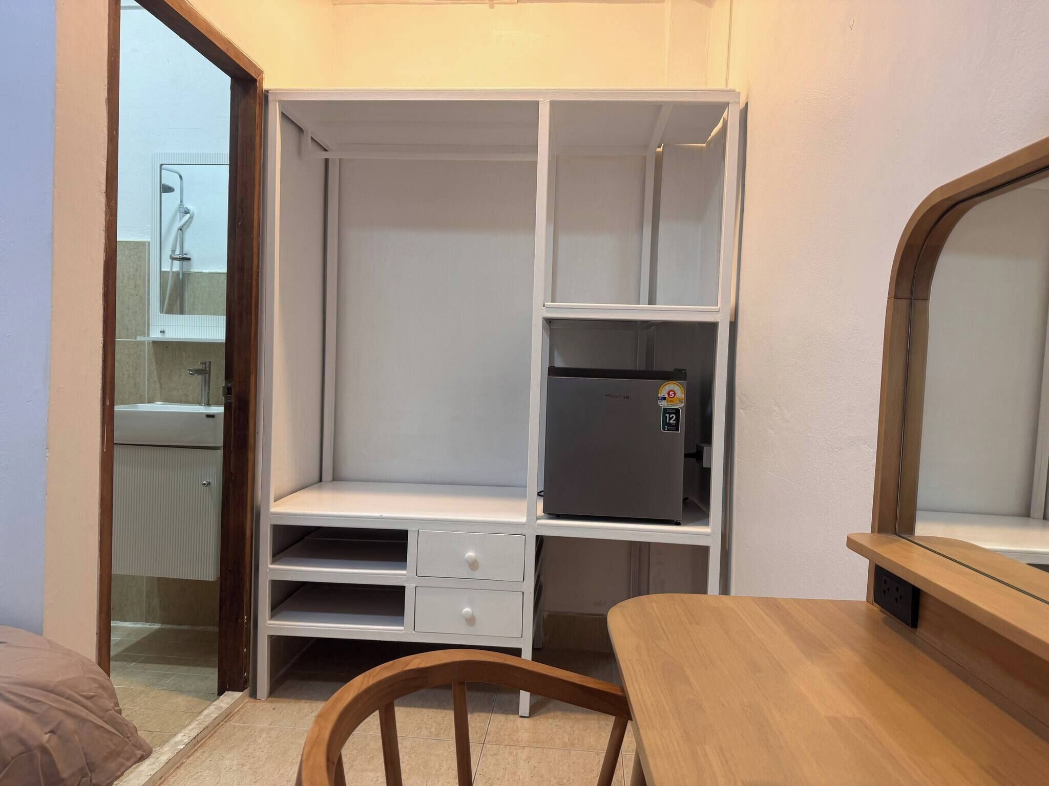 A compact room with a kitchenette, a wooden chair, and a small table.