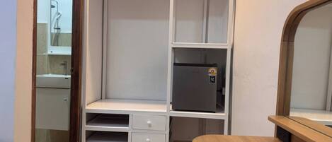A compact room with a kitchenette, a wooden chair, and a small table.