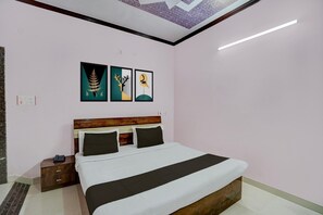 Une chambre à coucher comprenant un lit, une table de chevet, une tête de lit et trois œuvres d’art accrochées au mur.