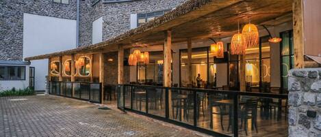 A restaurant with outdoor seating, stone walls, and hanging lights.