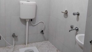 A small, tiled bathroom with a toilet, bidet, and sink.