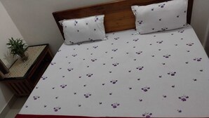 A bed with a floral bedspread, two pillows, and a wooden headboard.