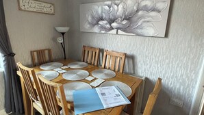 Un comedor con mesa de madera, sillas, individuales y un menú.