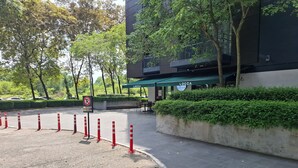 A parking area with a no parking sign, a building with a green awning labeled 'LOCCA,' and a landscaped area with trees and bushes. - Cyberjaya Tamarind Suites, Mediya Homestay (Cyberjaya)