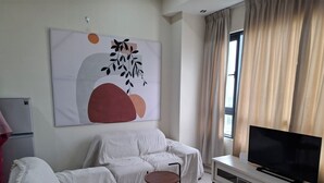 A modern living room with a sofa, a TV, a small table, and a painting on the wall. - Cyberjaya Tamarind Suites, Mediya Homestay (Cyberjaya)