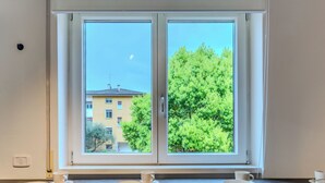A room with a large window, a radiator, and a table with plates and cups. - Family and Friends by Interhome (Riva del Garda)