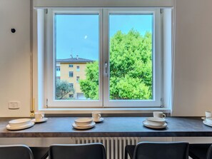 A room with a large window, a radiator, and a table with plates and cups. - Family and Friends by Interhome (Riva del Garda)