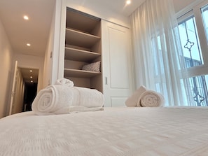 Une chambre à coucher avec un lit, une grande fenêtre et une armoire.