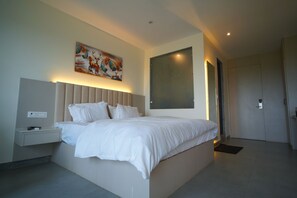 Une chambre à coucher moderne avec un grand lit, des tables de chevet, un tableau accroché au mur et une porte.