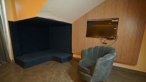 A room with a built-in seating area, a mounted television, and a single armchair.