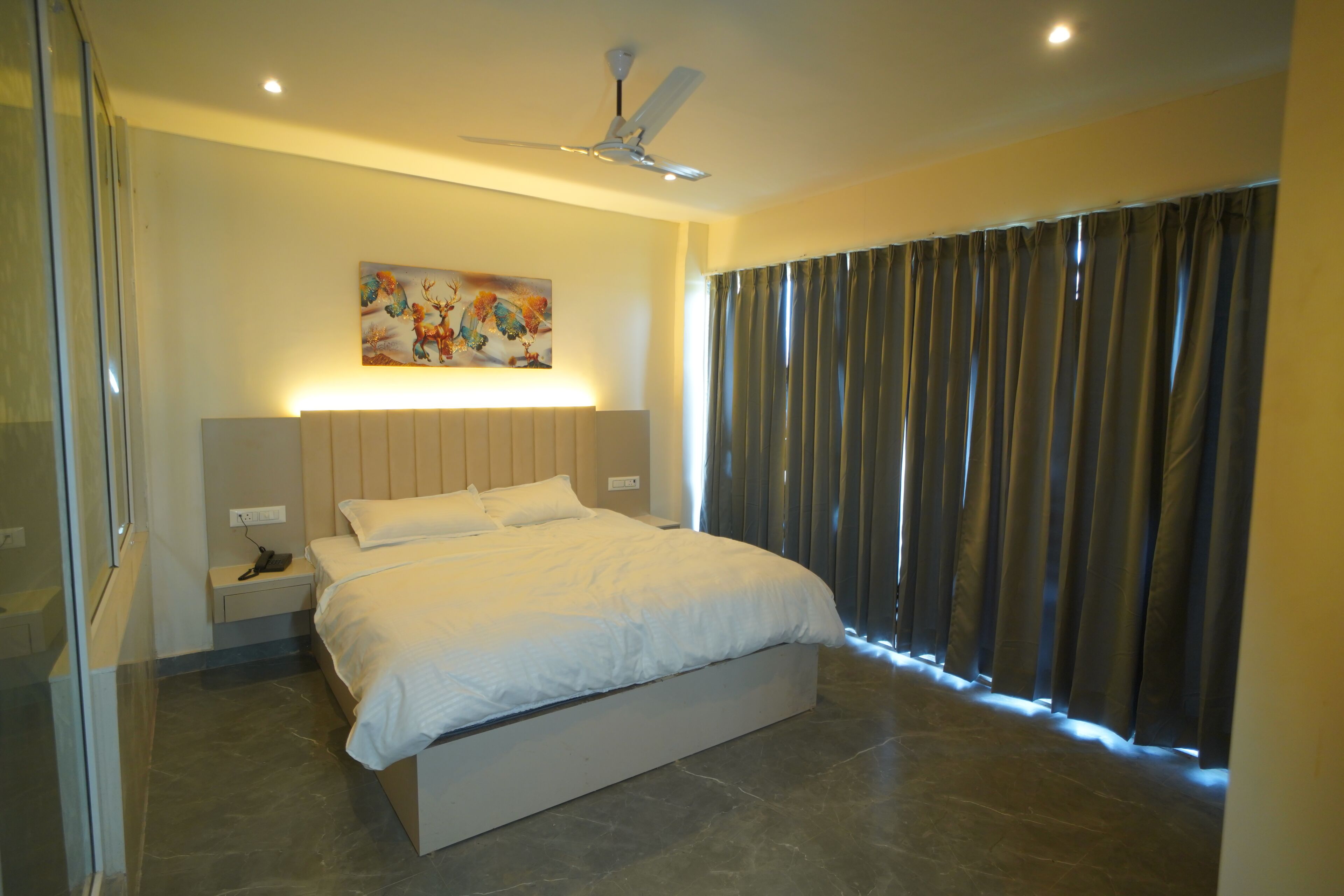 Un dormitorio moderno con una cama grande, un ventilador de techo, una mesita de noche y un cuadro en la pared.