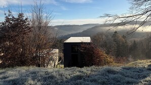 A small cabin with a sloped roof, surrounded by trees and a mountainous landscape. - Brand new: Eco-logement Koda Loft 2 - Introductory price! (Hommert)