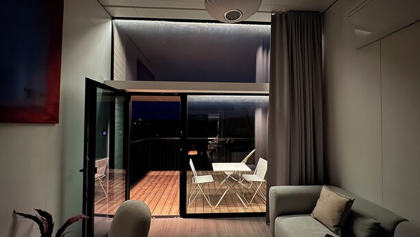A modern living room with a glass door leading to an outdoor deck, a sofa, and a dining area. - Brand new: Eco-logement Koda Loft 2 - Introductory price! (Hommert)