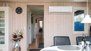 Een kamer met een eettafel, stoelen, een vaas met bloemen, een klok en een airconditioner.