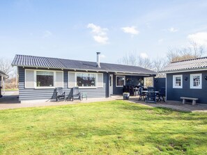 A two-story house with a patio area, outdoor seating, and a visible chimney. - 5 Person Holiday Home in Hemmet (Hemmet)