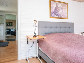 A bedroom with a bed, a bedside table with a lamp, a framed artwork on the wall, and a view into the adjacent living area. - 5 Person Holiday Home in Hemmet (Hemmet)