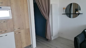 Cozinha moderna com armários de madeira, forno embutido e um espelho acima de uma prateleira.