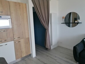 A modern kitchen with wooden cabinets, a built-in oven, and a mirror above a shelf. - 2 steps from the beach, with a privileged view of the sea and the Vendée coast! (Saint-Hilaire-de-Riez)
