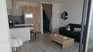 Cozinha moderna com eletrodomésticos embutidos, área de refeições com mesinha de centro e um sofá preto.